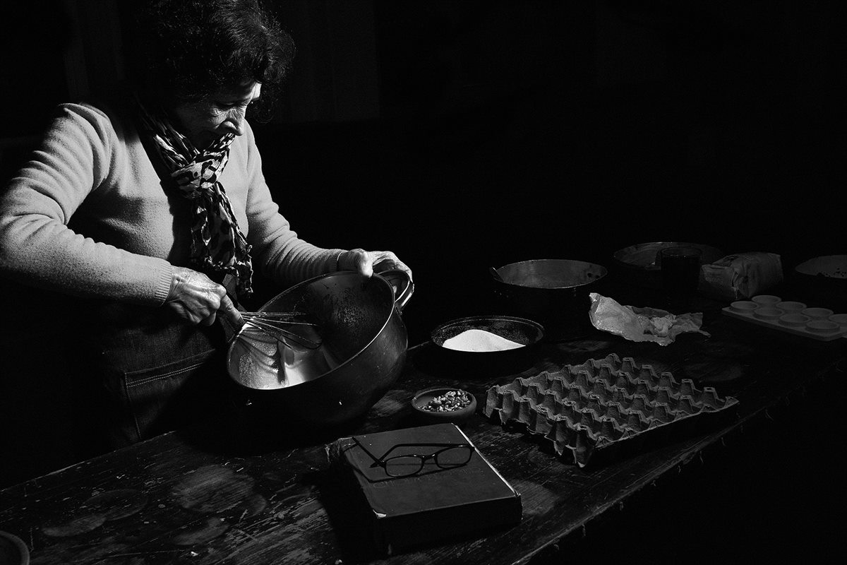 Blanca Lanzy en blanco y negro, con una fuente y un batidor, junto a un maple de huevos y un libro con anteojos