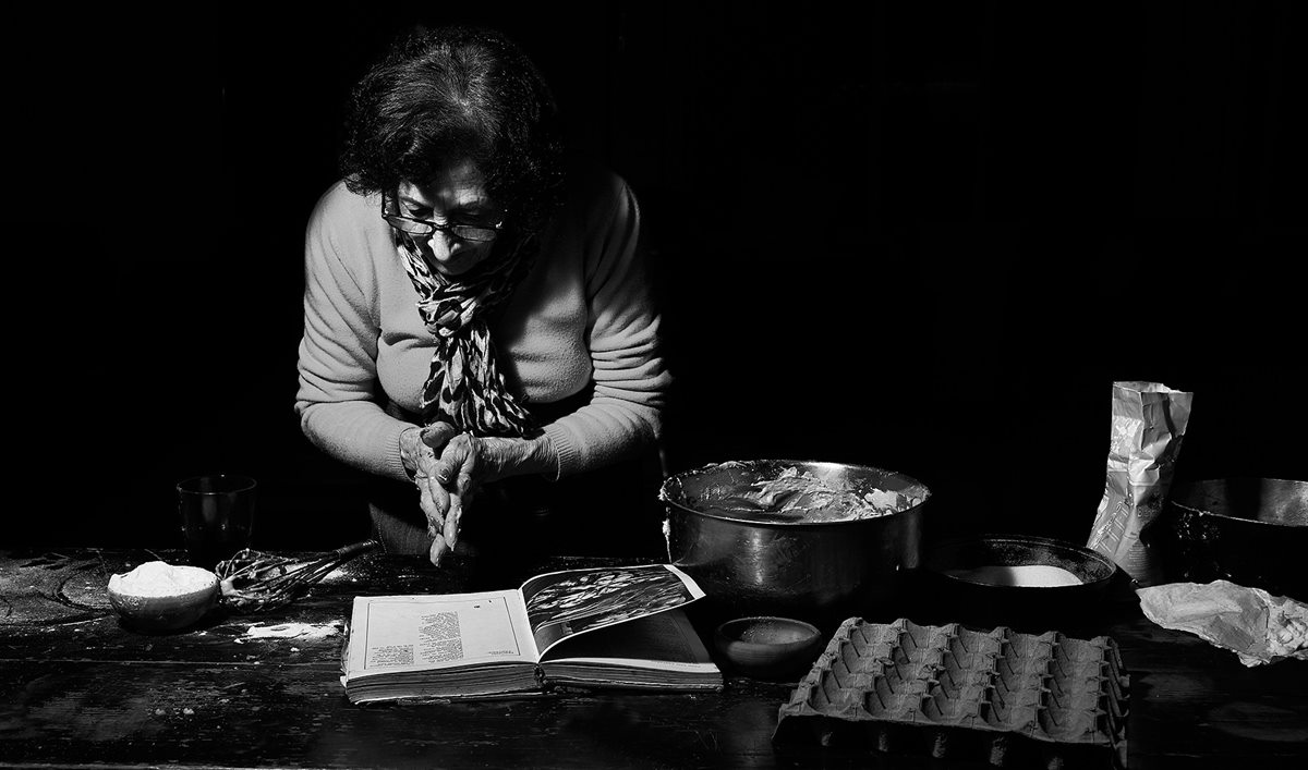 Blanca Lanzy en blanco y negro, con anteojos, inclinada sobre un libro abierto en una mesa de madera