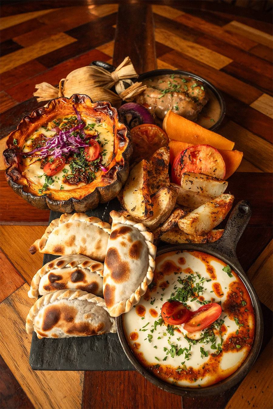 Tabla Andina con humita en cuenco de calabaza, empanadas, papas especiadas y cazuela de queso de cabra